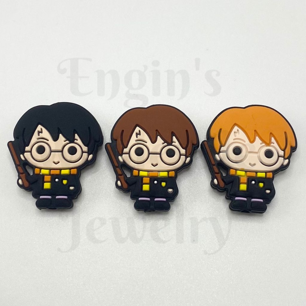 Three cartoon-style figurines of Harry Potter with different hair colors on a white background.