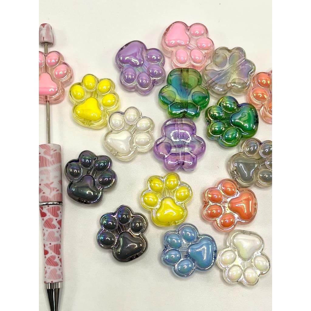 Colorful paw-shaped charms on a white background with a pen.