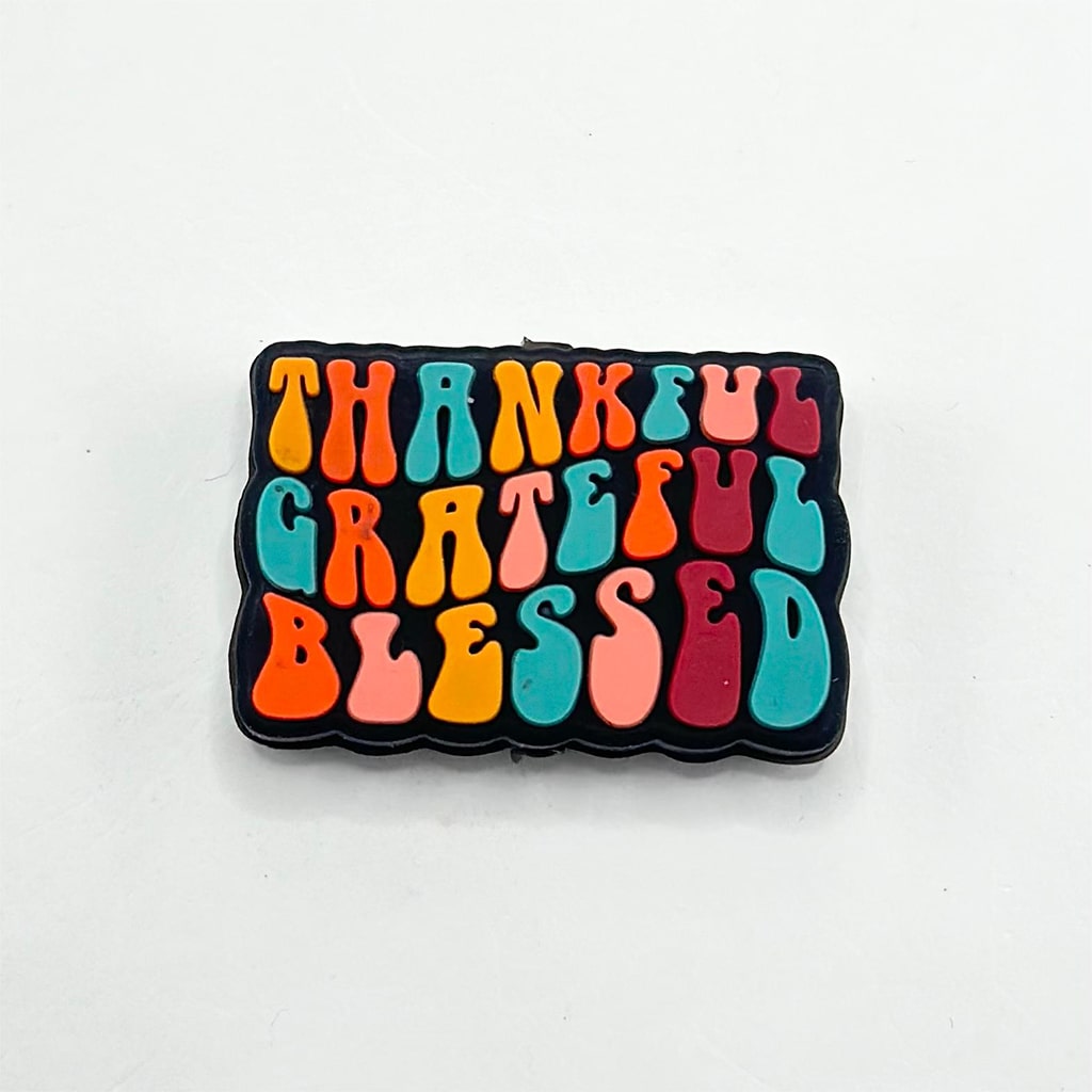 A rectangular silicone bead with the words 'THANKFUL' and 'Blessed' written in a colorful font.