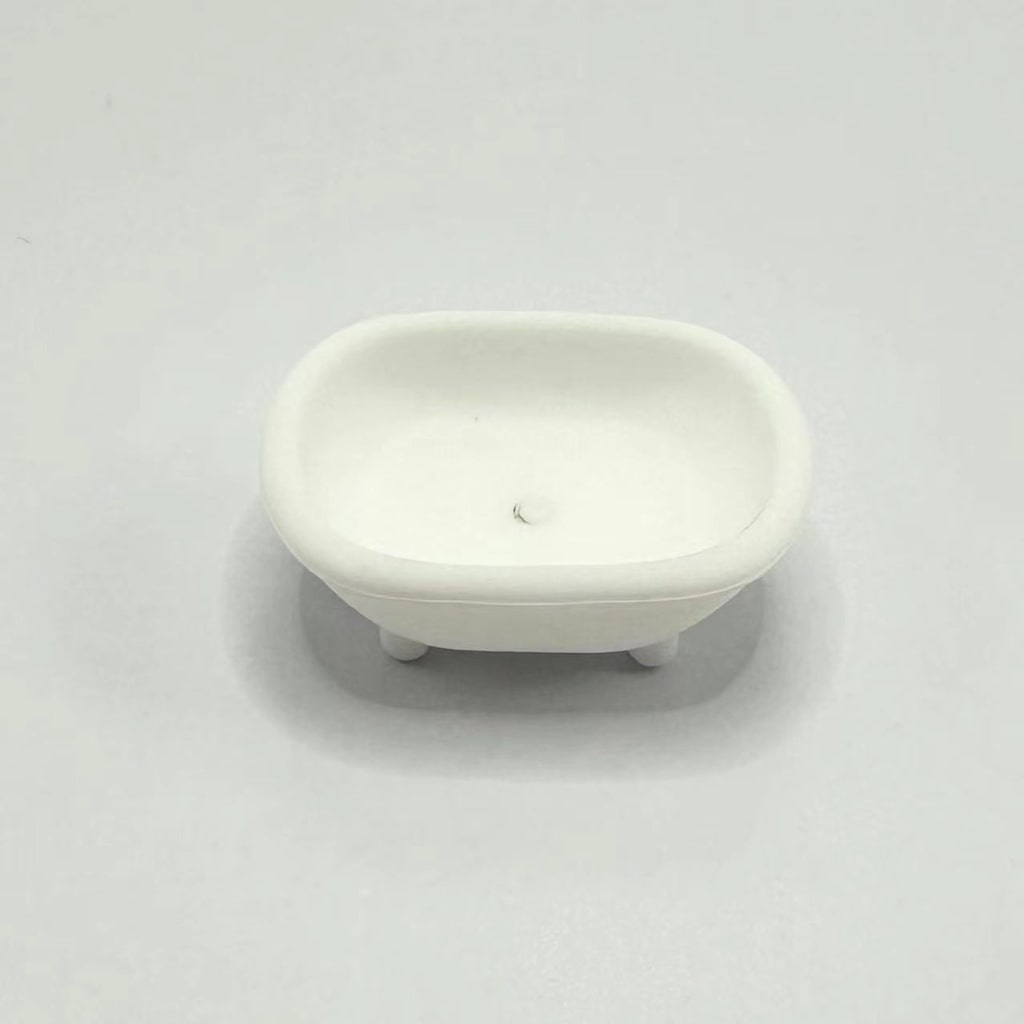 A small white silicone bead shaped like a bathtub focal bead, placed on a white surface.