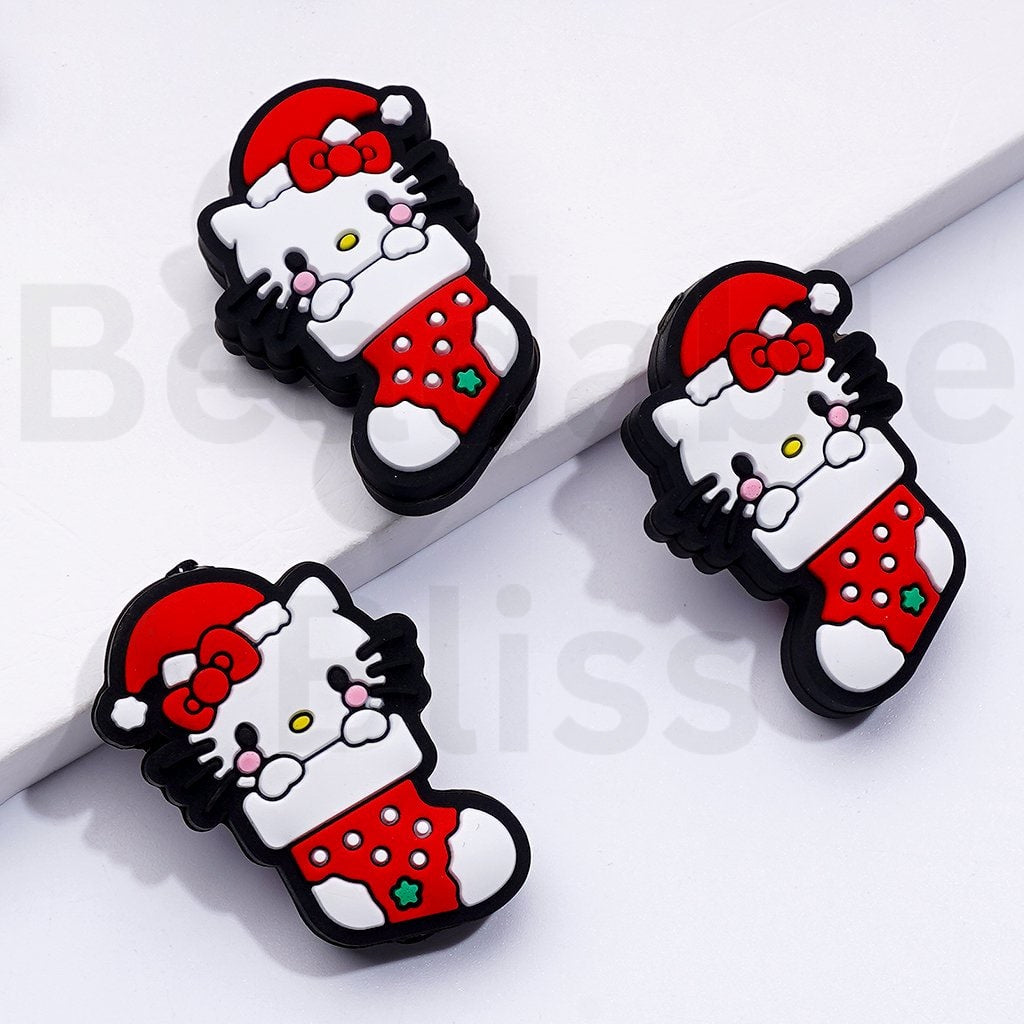 赤いクリスマス帽子をかぶったかわいい香港の子猫が赤いクリスマスソックスのシリコンフォーカルビーズに座っています