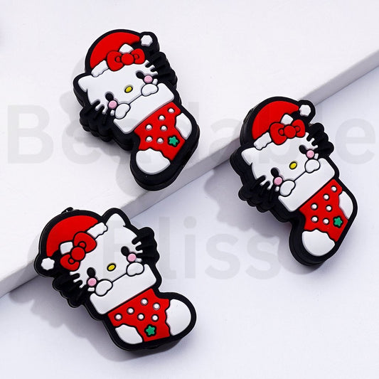 赤いクリスマス帽子をかぶったかわいい香港の子猫が赤いクリスマスソックスのシリコンフォーカルビーズに座っています