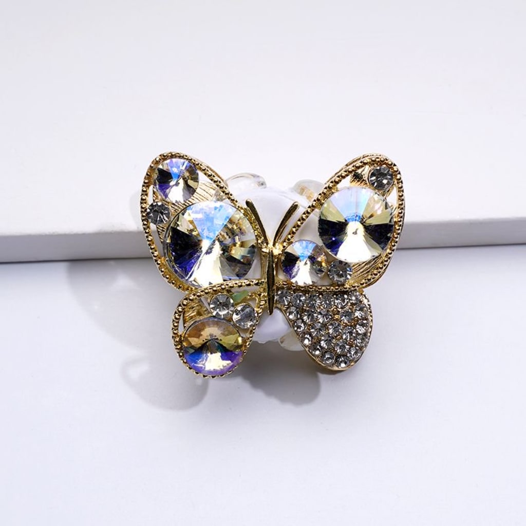 A gold alloy butterfly with red clear shiny rhinestones clay beads, against a white background.