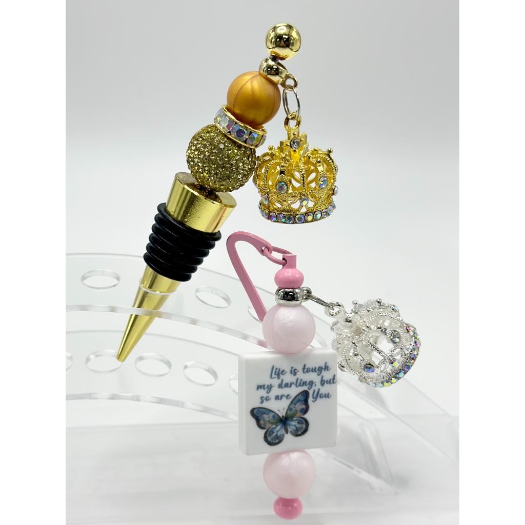 A selection of large metal crown pendants in gold and silver colors, accompanied by other beadable jewelry components displayed on a white surface.