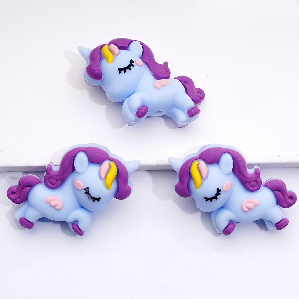 Three cartoon unicorn figurines with purple manes on a white background
