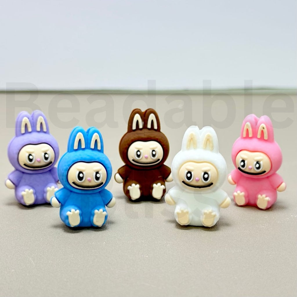 Five colorful cartoon character figurines in bunny costumes on a light gray background.
