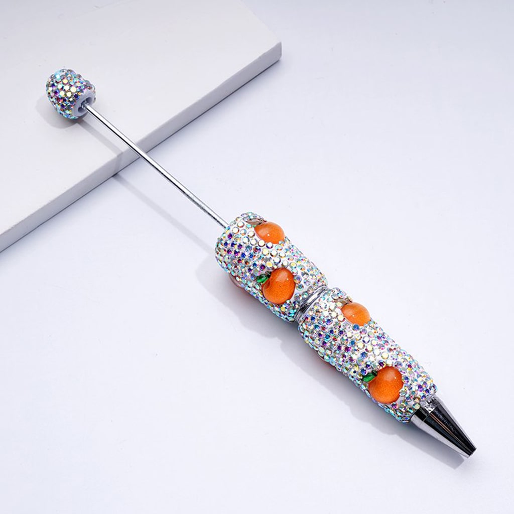 Decorative pen with gemstones and orange accents on a white background