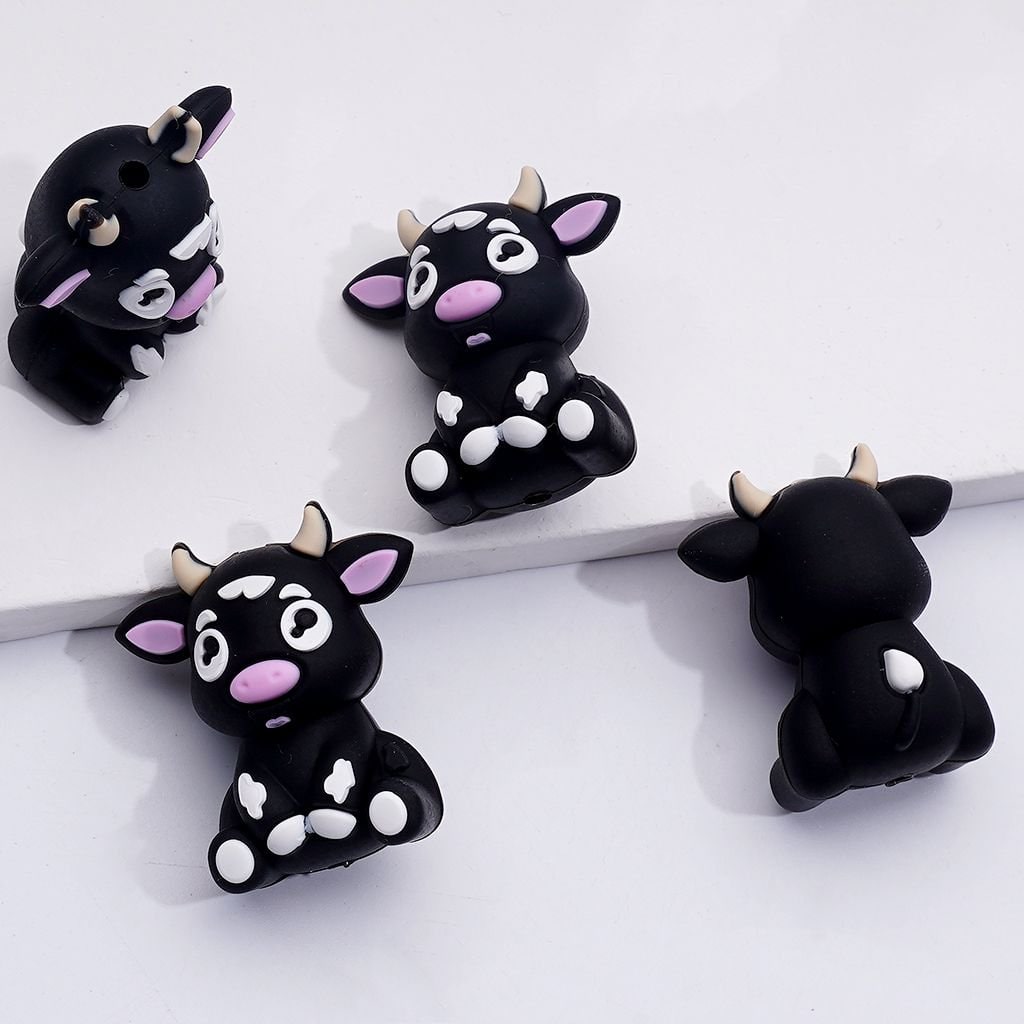 Four black cow-shaped phone cases with white and pink accents on a white background