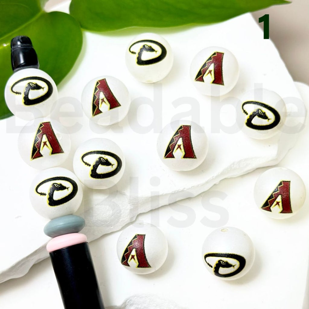 White beads with logos on a white surface with a green leaf in the background