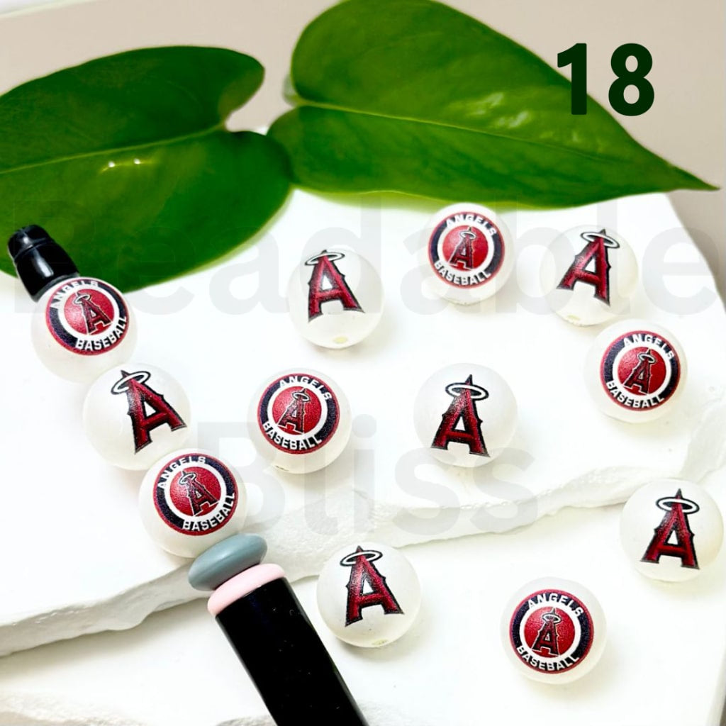 Set of Los Angeles Angels baseball-themed lip balms on a white surface with green leaves in the background.