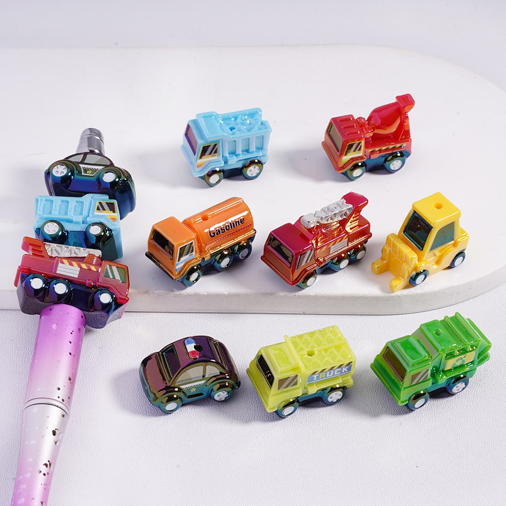 Colorful toy cars arranged on a white surface with a pen.