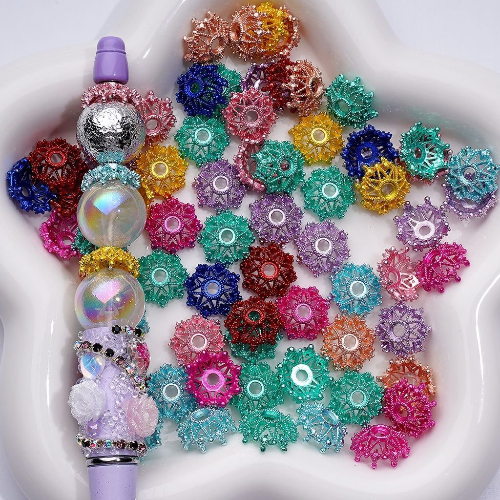 A collection of multicolored acrylic crown bead caps displayed in a petri dish, with some beads caps arranged on a pen for scale.