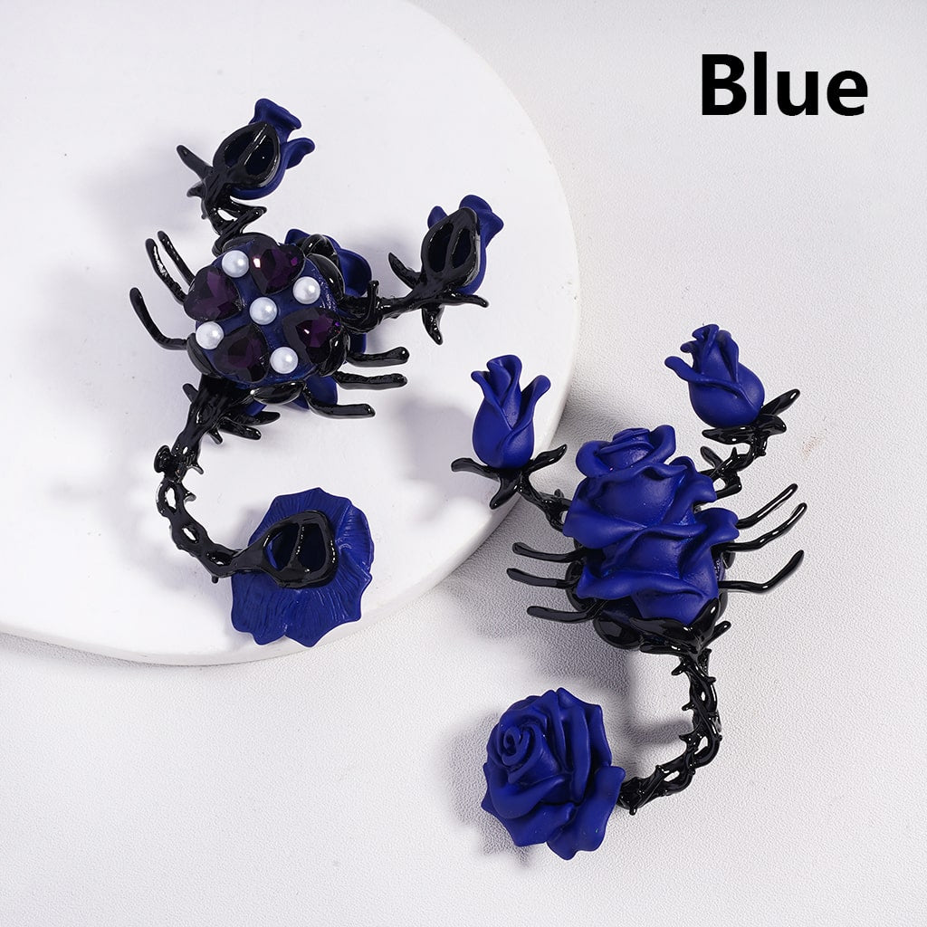 Black and blue rose-shaped earrings on a white plate with 'Blue' text.