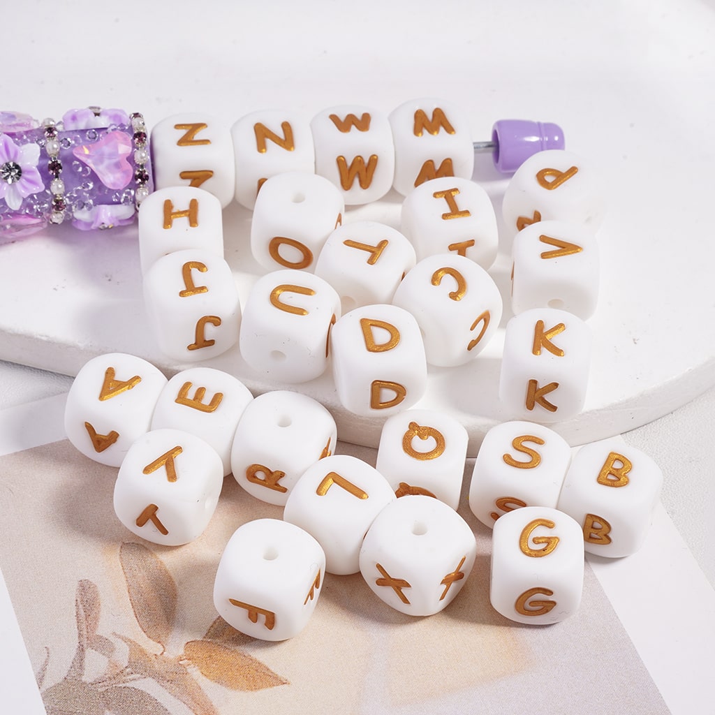 White letter beads with gold letters on a white surface