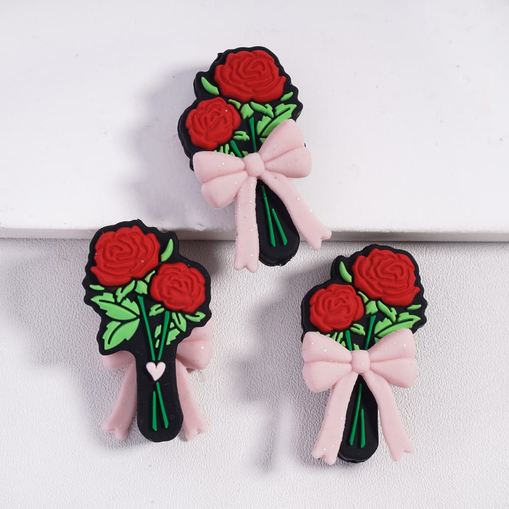 Three decorative hair clips with red roses and pink bows on a white background