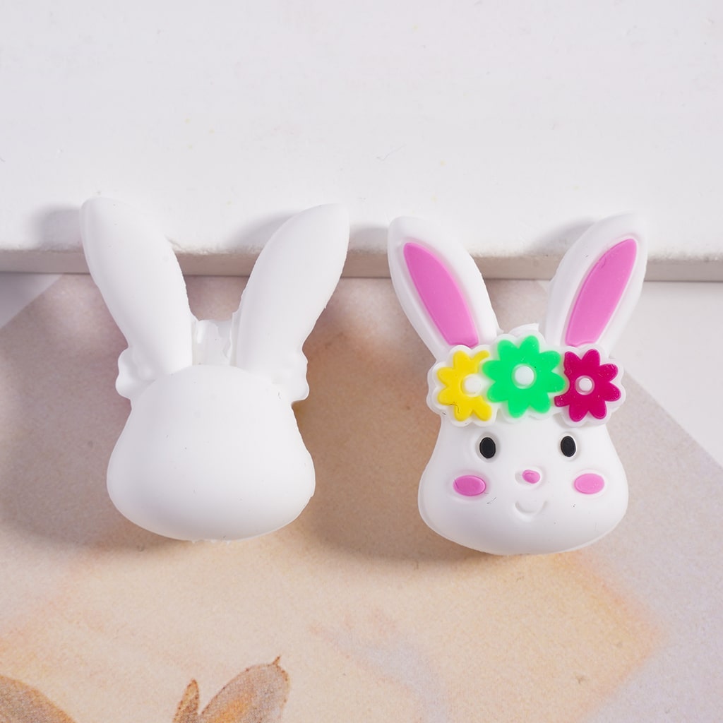 Two white rabbit-shaped phone holders with colorful flower headbands on a light background.