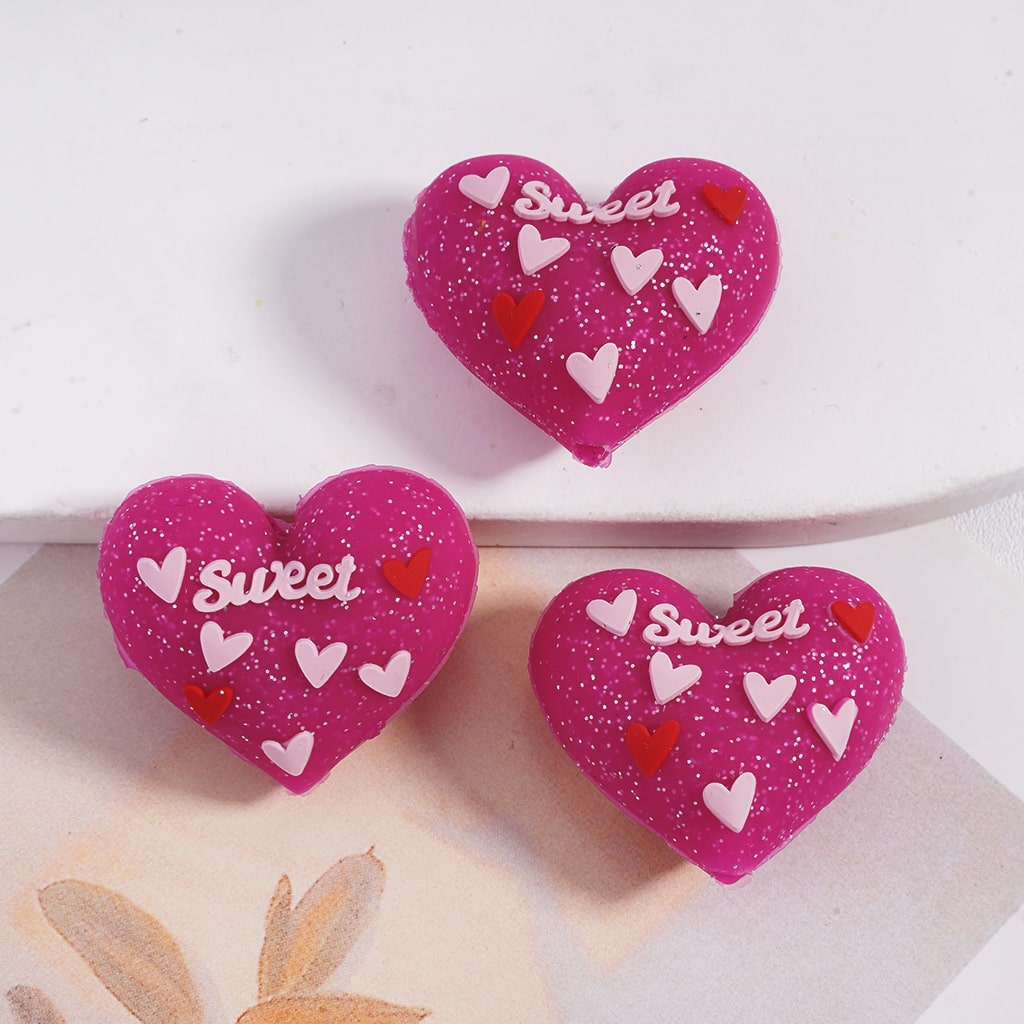 Three pink heart-shaped cookies with 'sweet' text and heart decorations on a white surface.