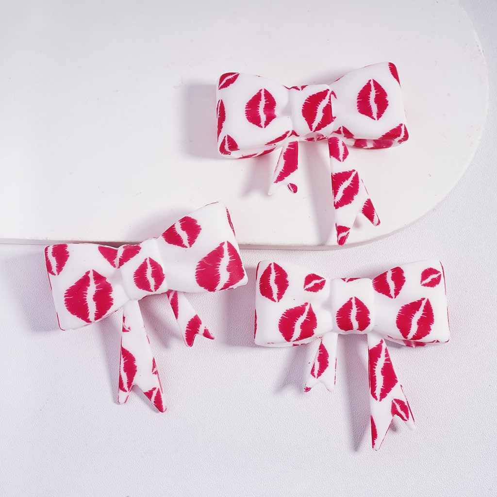 Three hair bows with red kiss mark pattern on a white background
