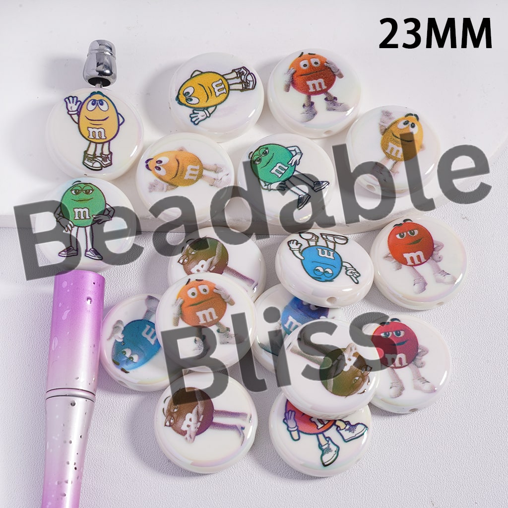 Set of M&M-themed buttons on a white background with a pen.