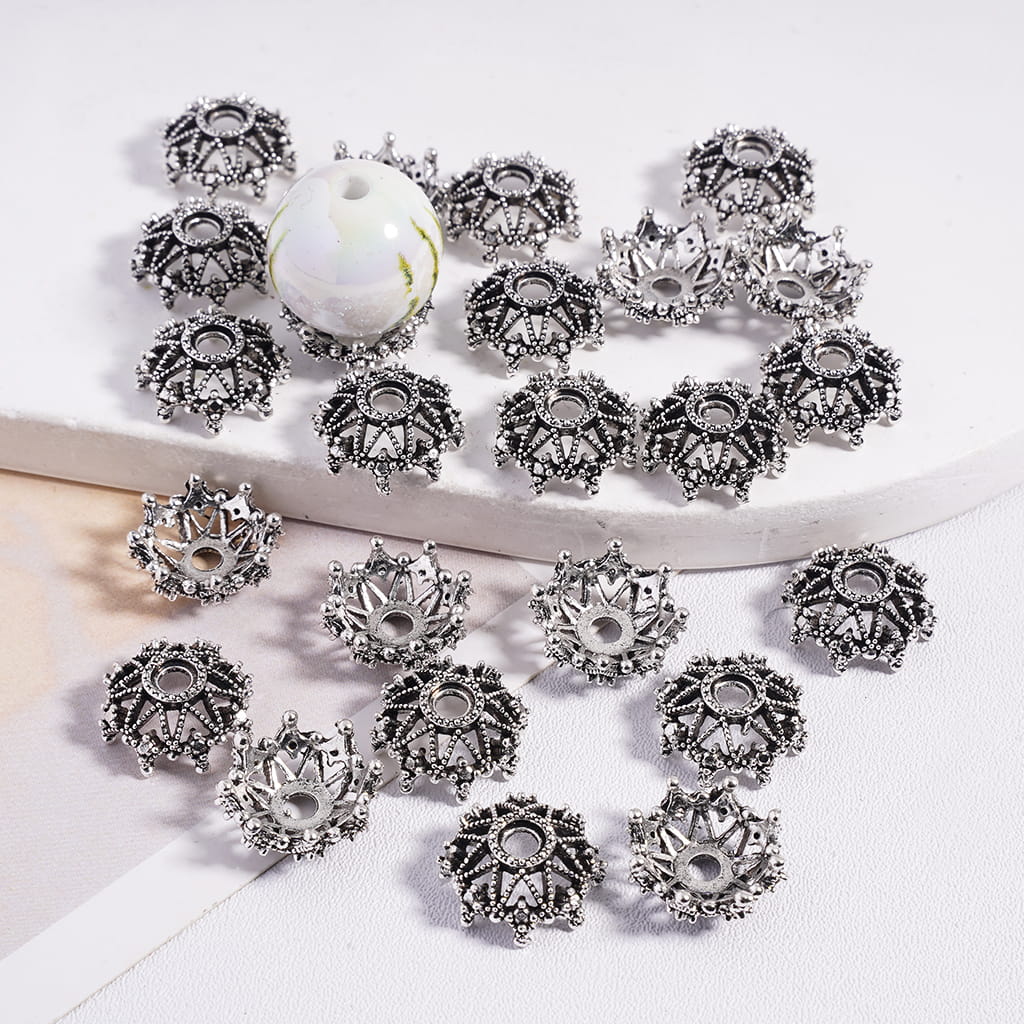 Decorative silver beads with intricate designs on a white surface