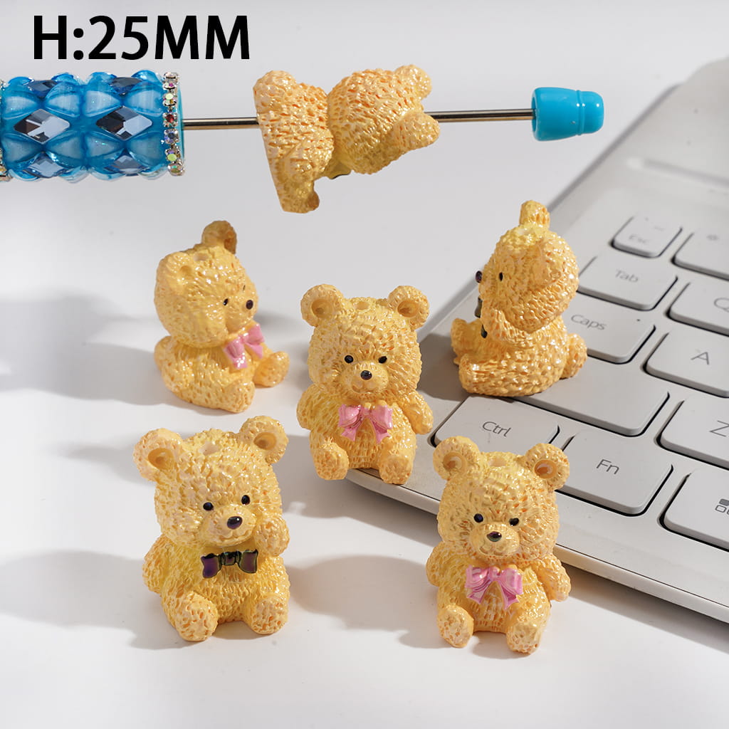 Five small teddy bear figurines with a laptop and water bottle in the background.