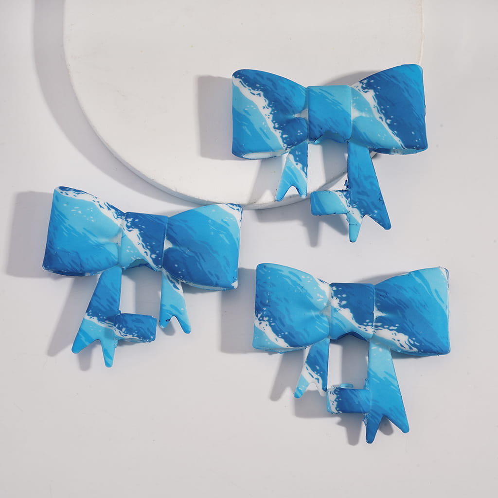 Three blue and white marbled hair bows on a light gray background