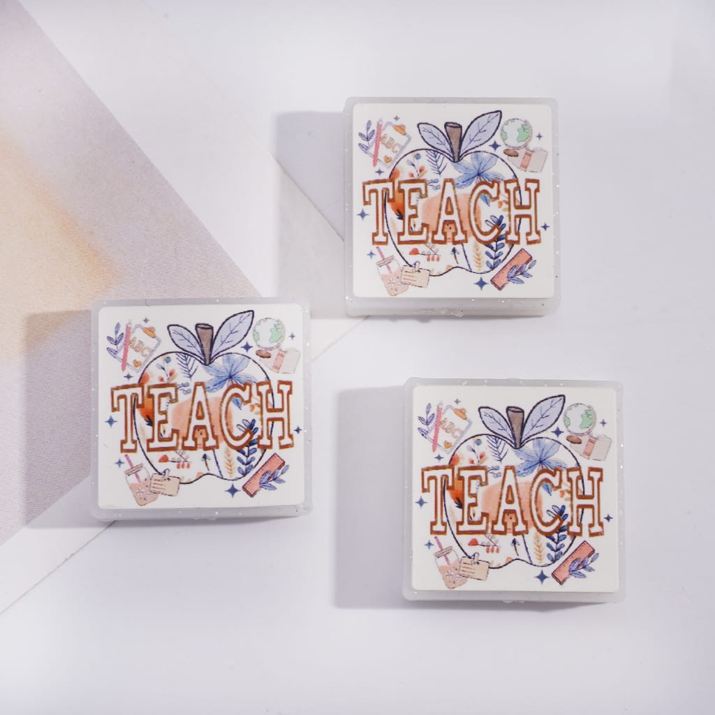 Three decorative blocks with 'TEACH' and apple illustrations on a white surface.