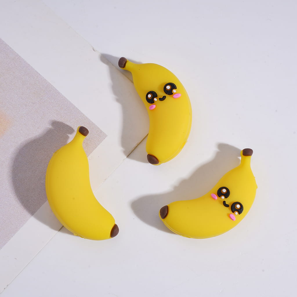 Three yellow banana-shaped earrings with smiling faces on a light background