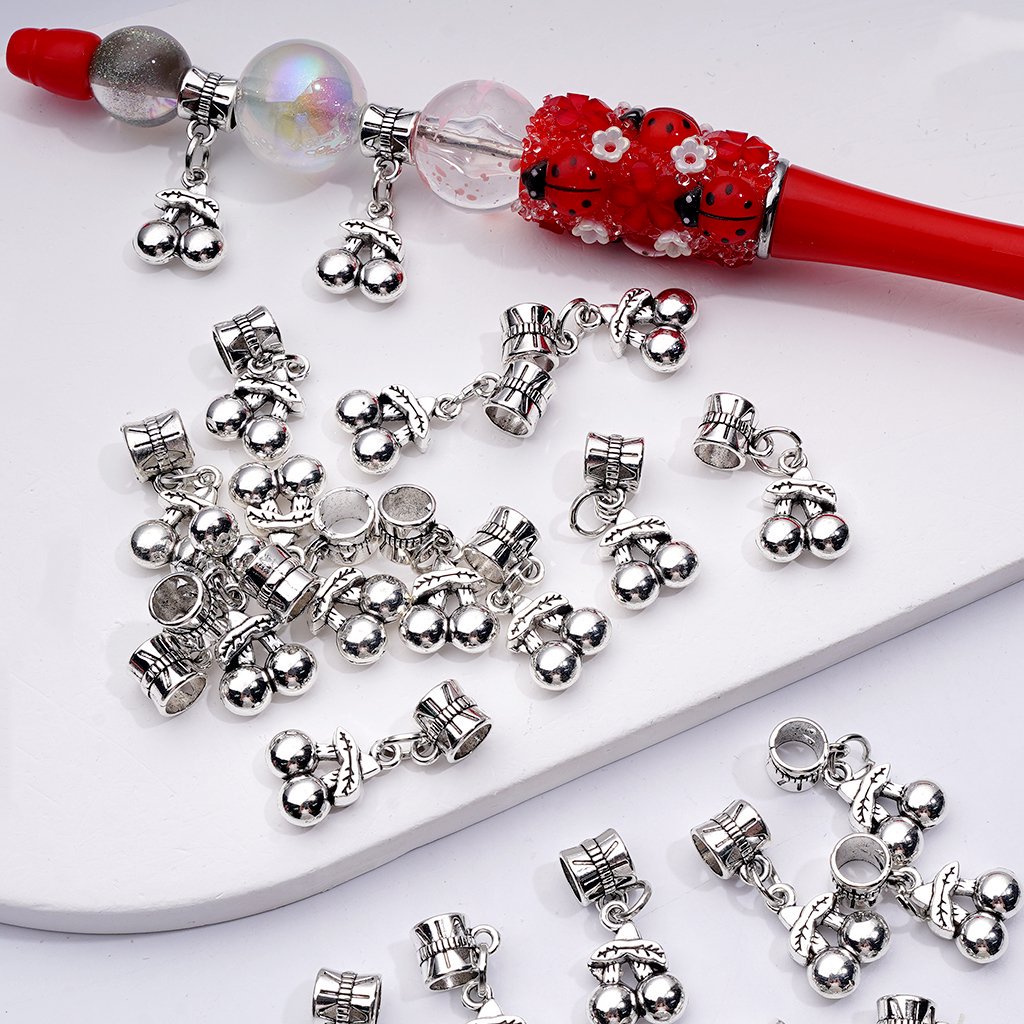 Silver charms resembling dogs on a white plate with a red hairbrush in the background