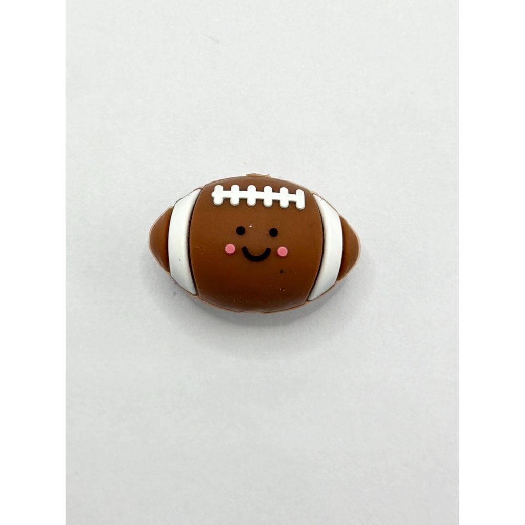 A silicone bead in the shape of a cute, smiling American football with white lines and a face printed on it.