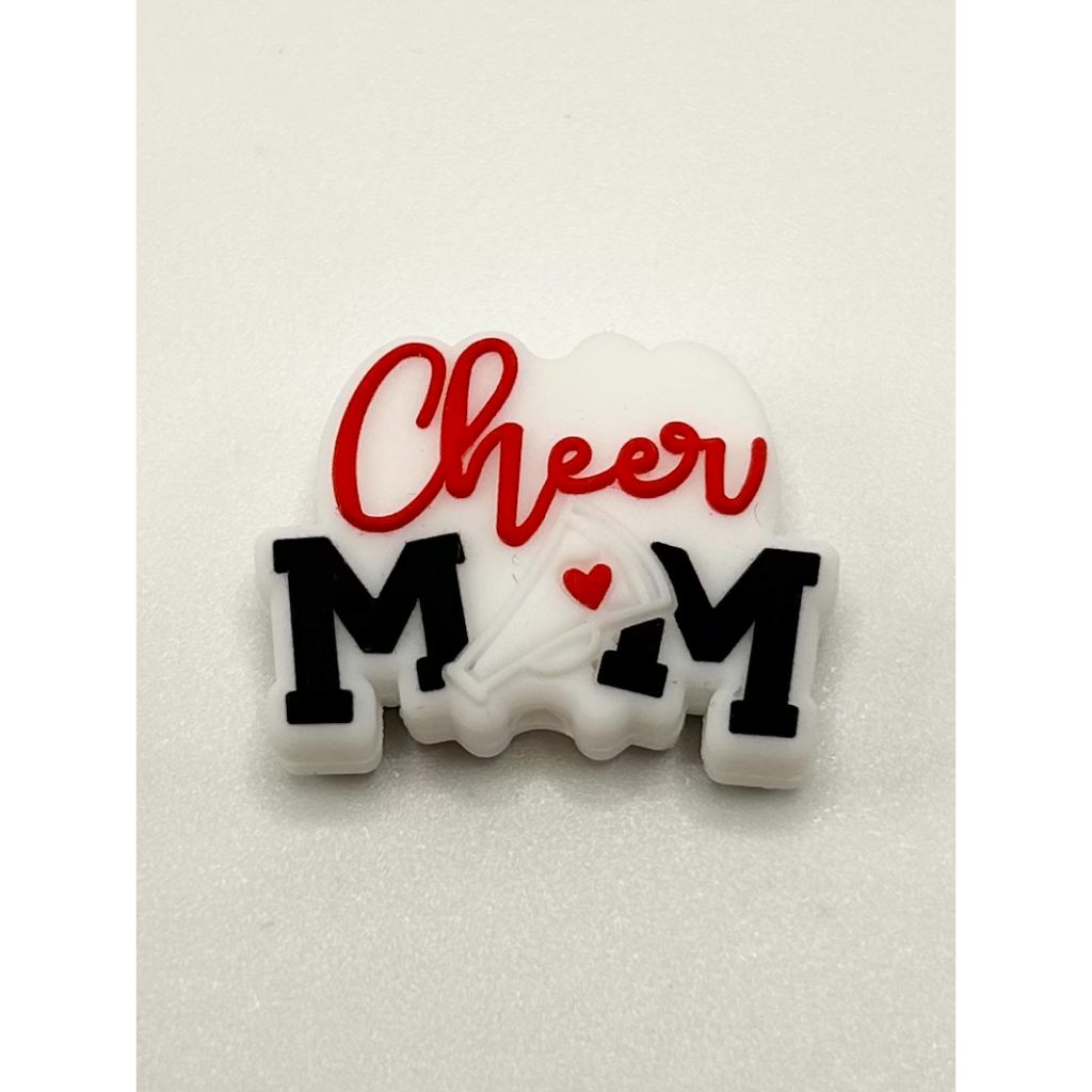 A silicone bead with the text 'Cheer MOM' written in red and white, with a heart symbol replacing the letter 'O'.