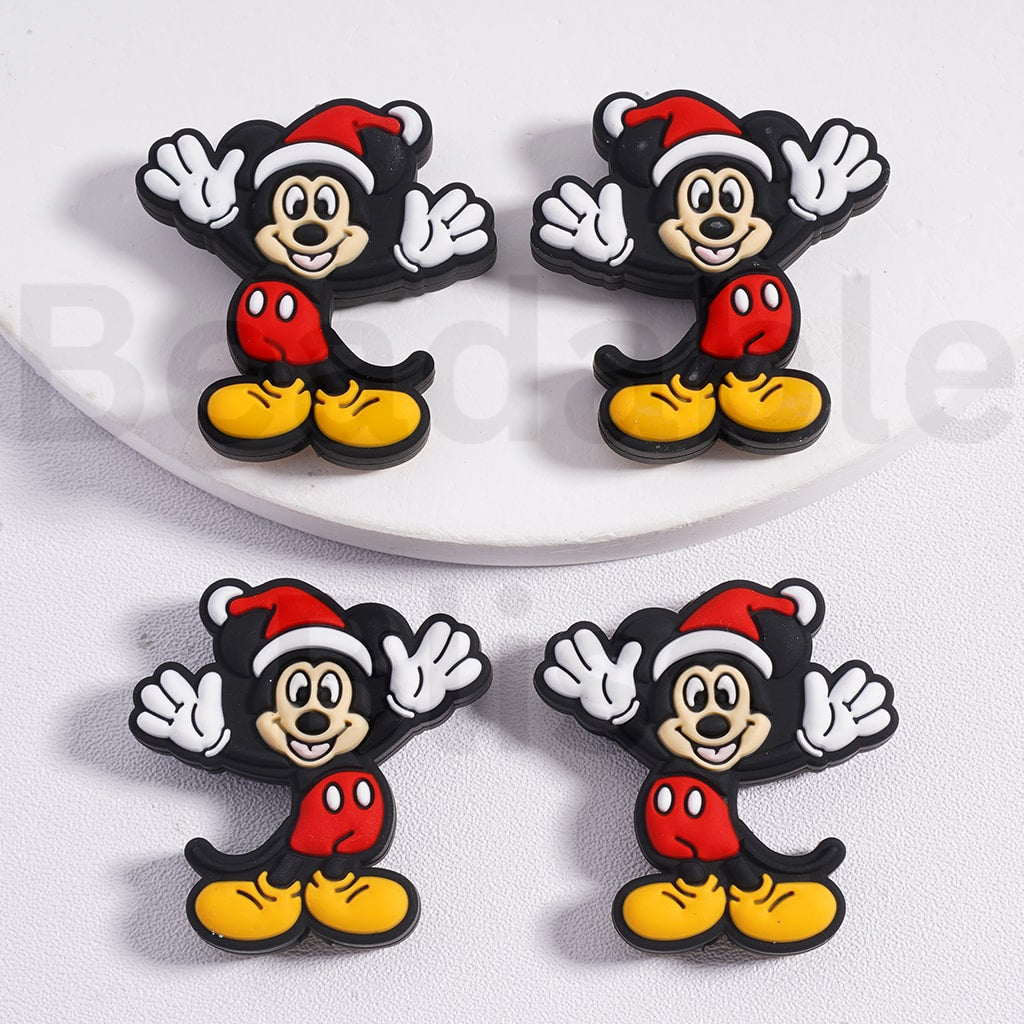 Four cartoon character earrings with Santa hats on a white plate.