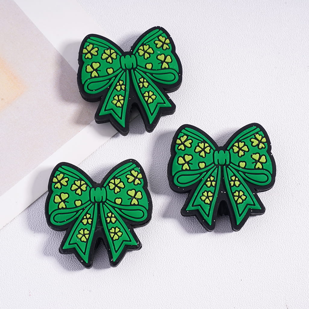 Three green bow-shaped pins with yellow patterns on a white background