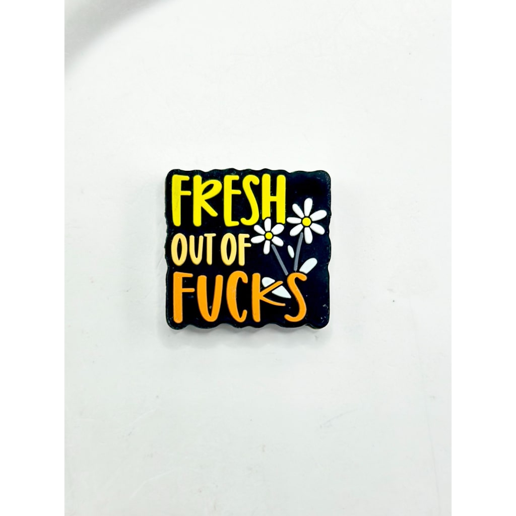 Black square patch with yellow text 'Fresh Out of Fucks' and white flowers on a white background