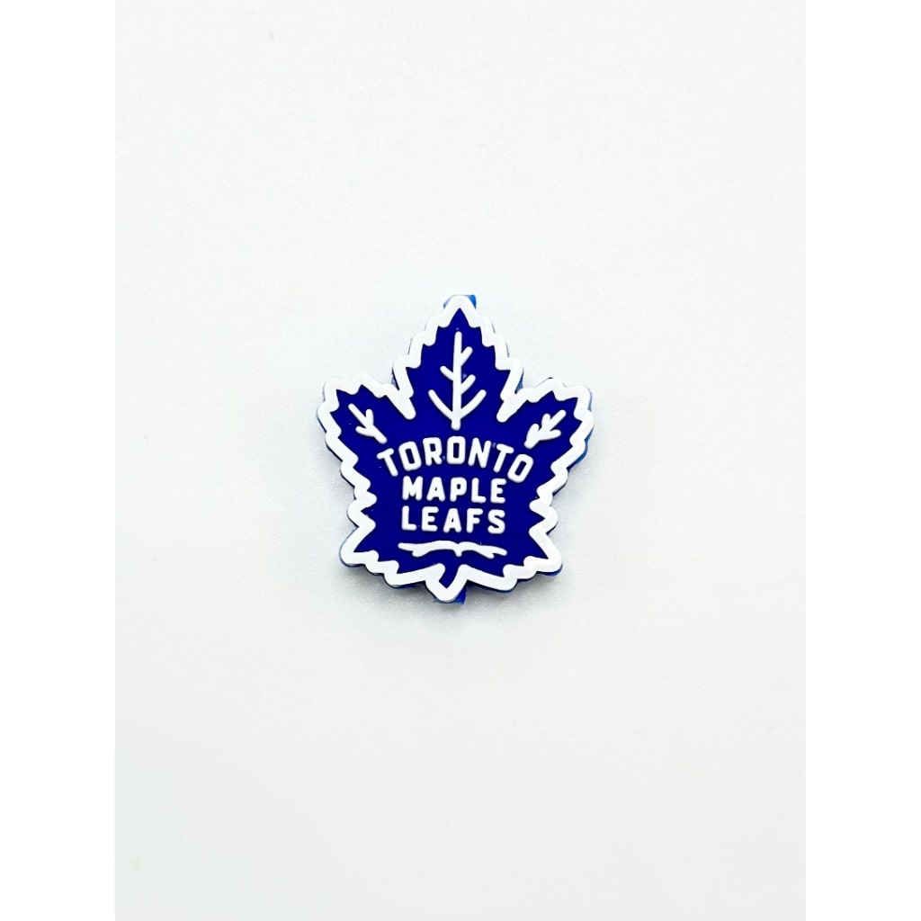 A silicone bead in the shape of a maple leaf with 'Toronto Maple Leafs' text in blue on a white background.