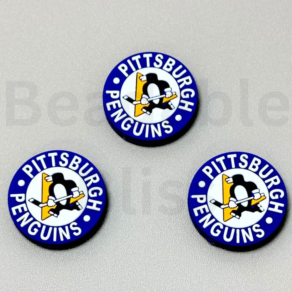 Three Pittsburgh Penguins buttons on a gray background