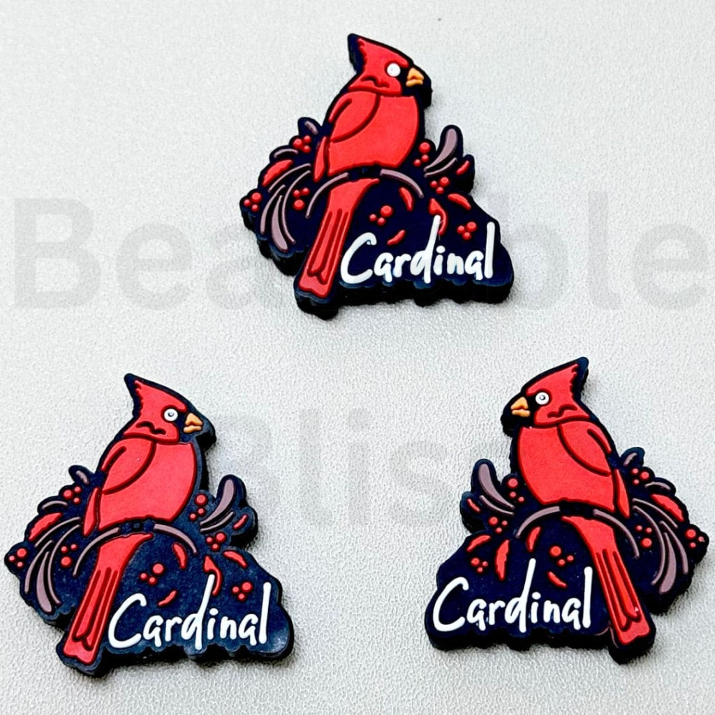 Three red cardinal bird pins with 'Cardinal' text on a light gray background.