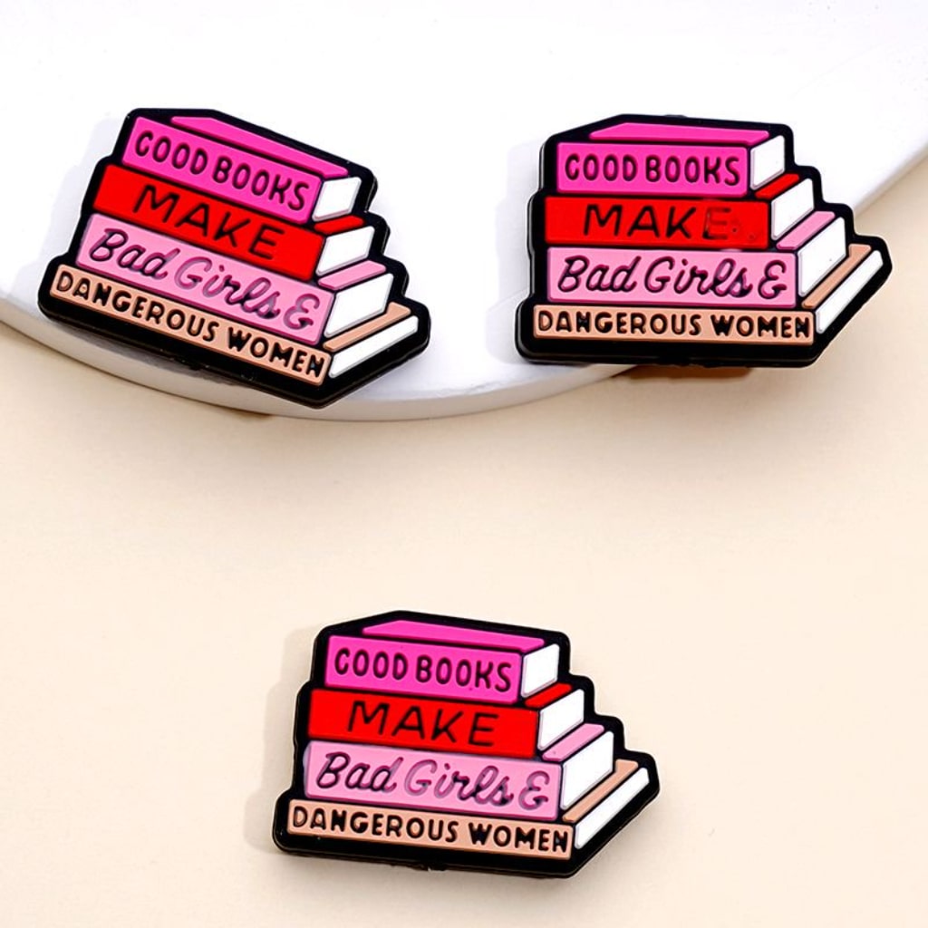 A set of silicone beads with the phrase 'Good Books Make Bad Girls Dangerous Women' printed on them, arranged in a stack.