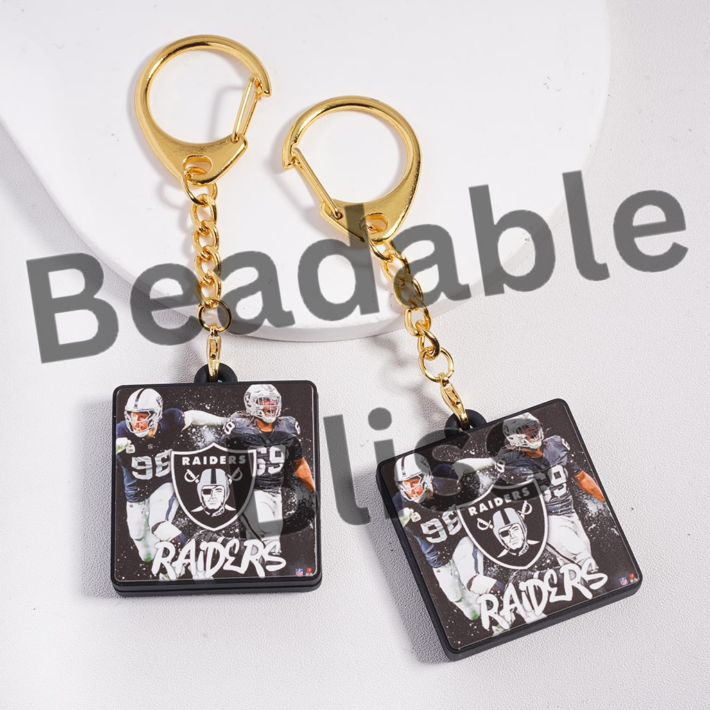 Two keychains with a Raiders logo and football players on a white background.