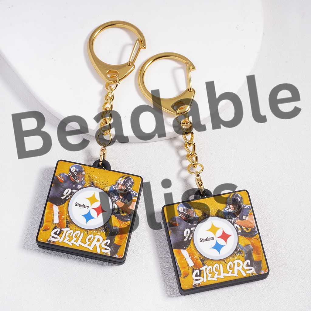 Pair of Steelers-themed keychains with gold hooks on a white background.