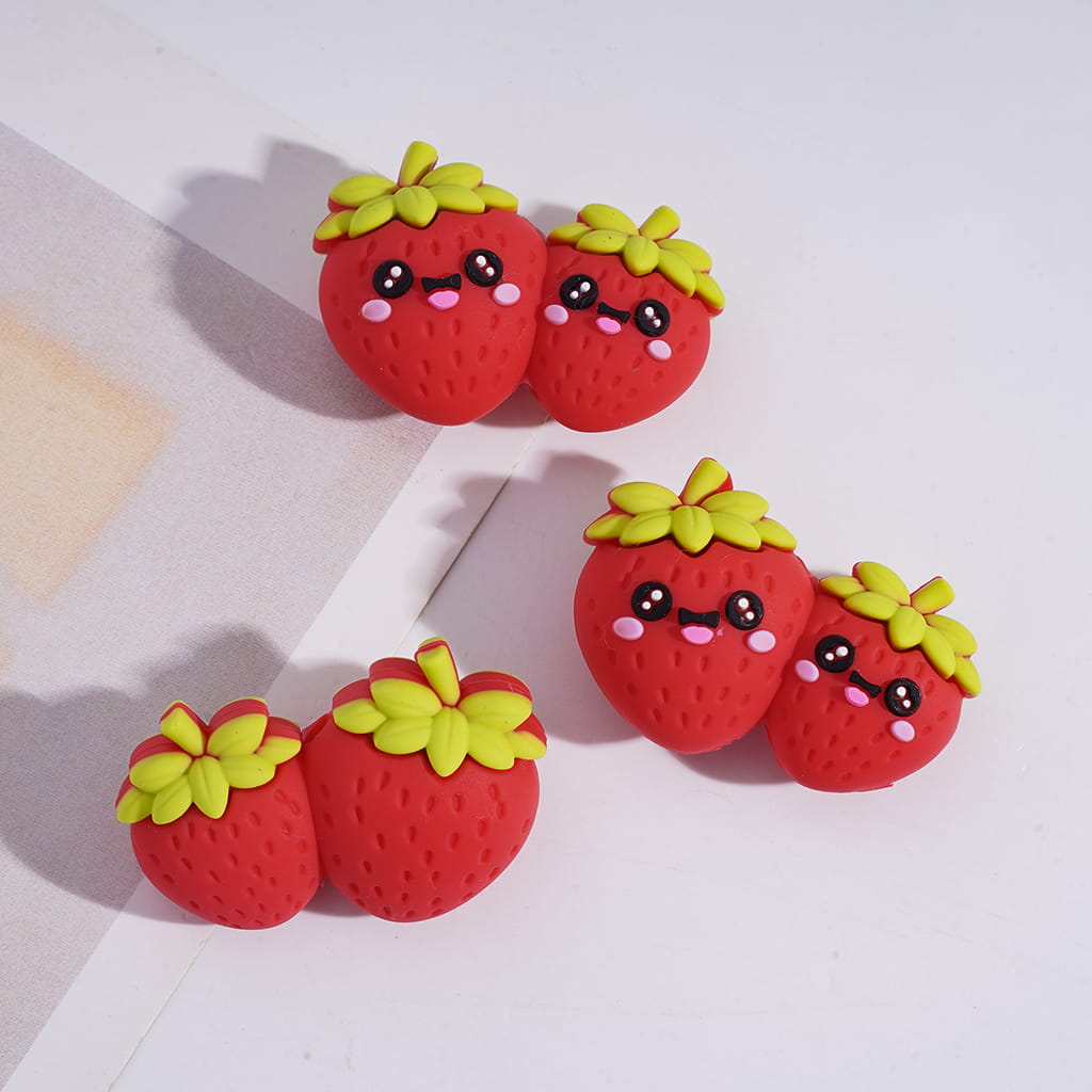 Four red strawberry-shaped earrings with green leaves on a light background
