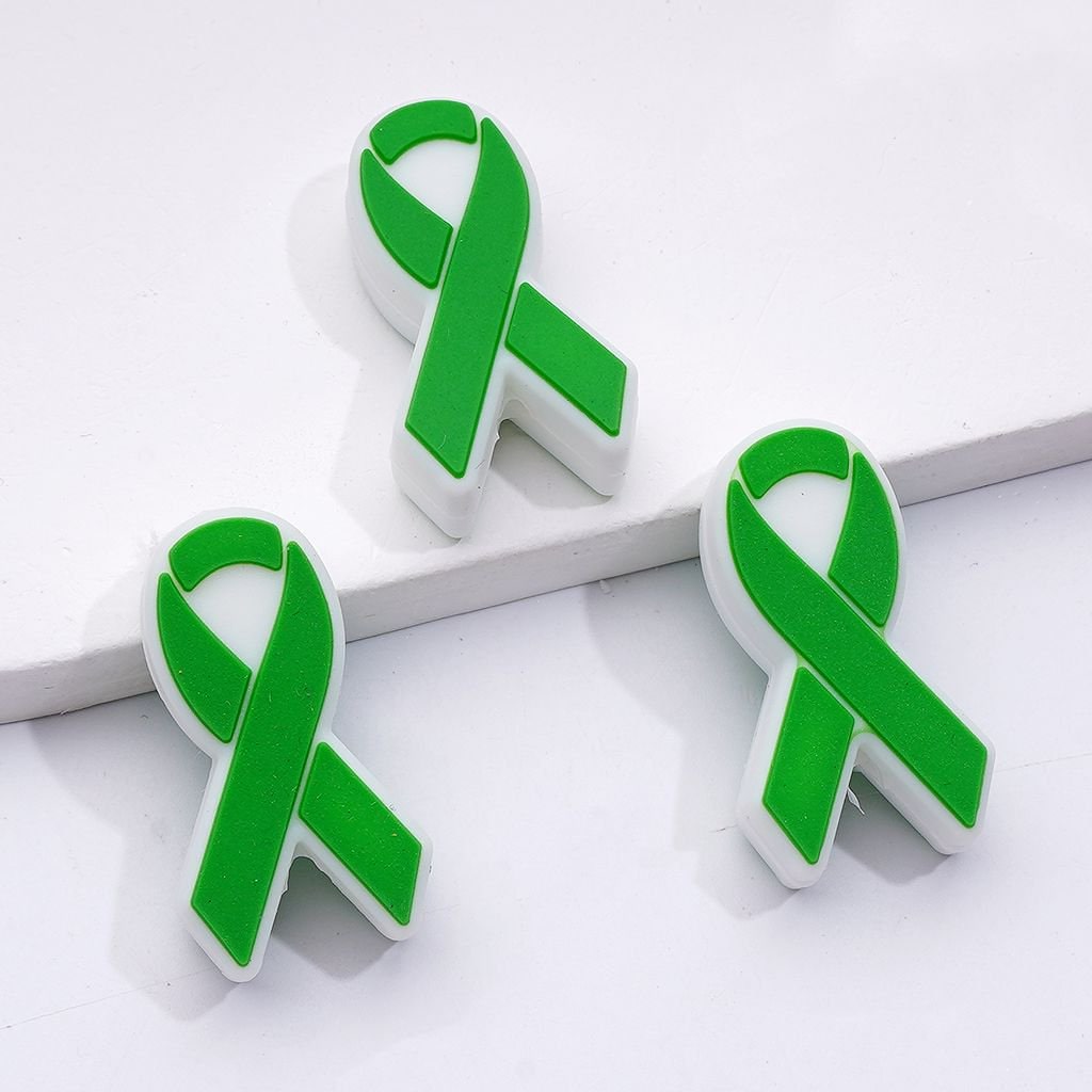 Green and white awareness ribbon pins on a white background