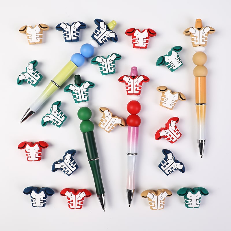 Colorful pen toppers shaped like cartoon shirts on a white background