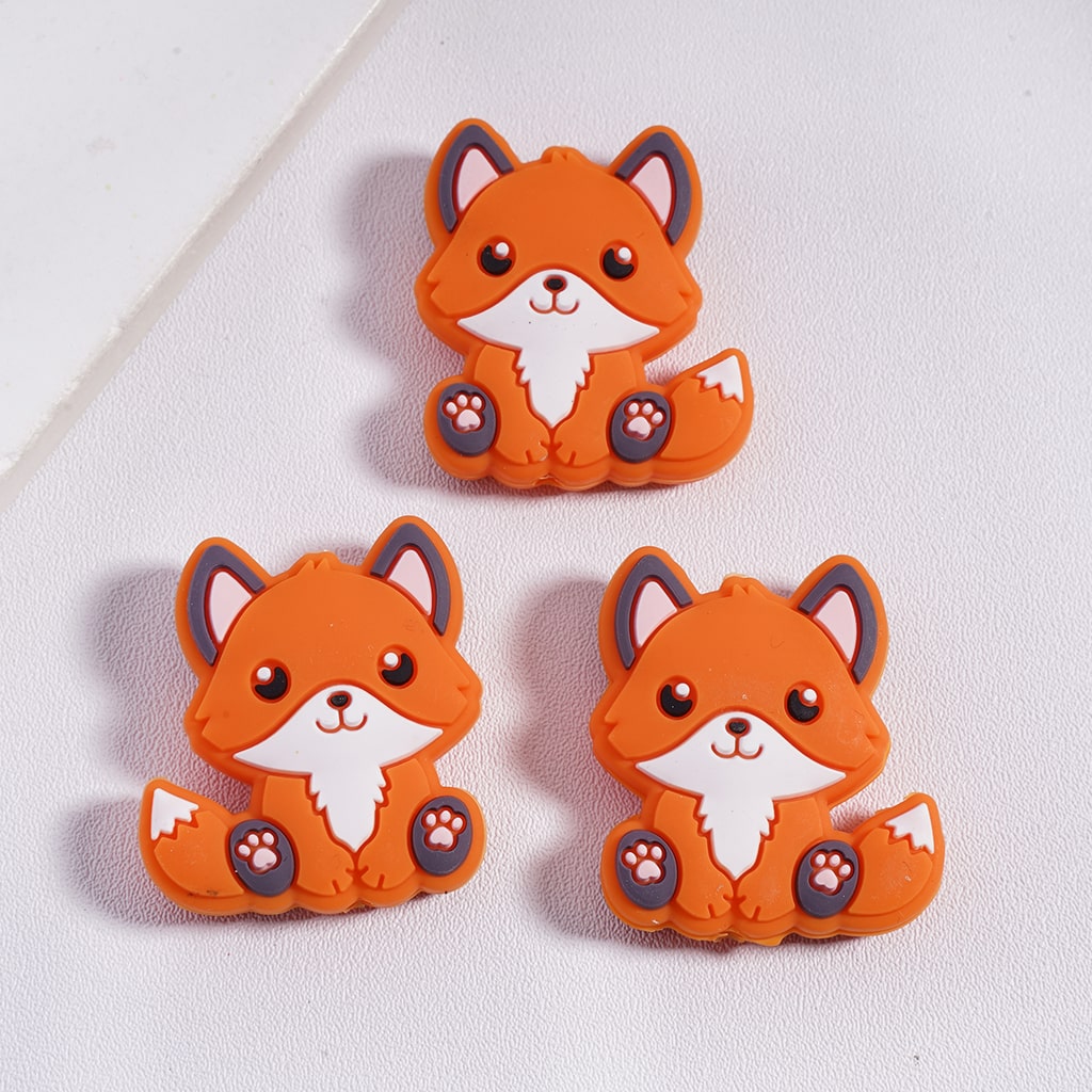 Three orange fox-shaped rubber bands on a light gray background