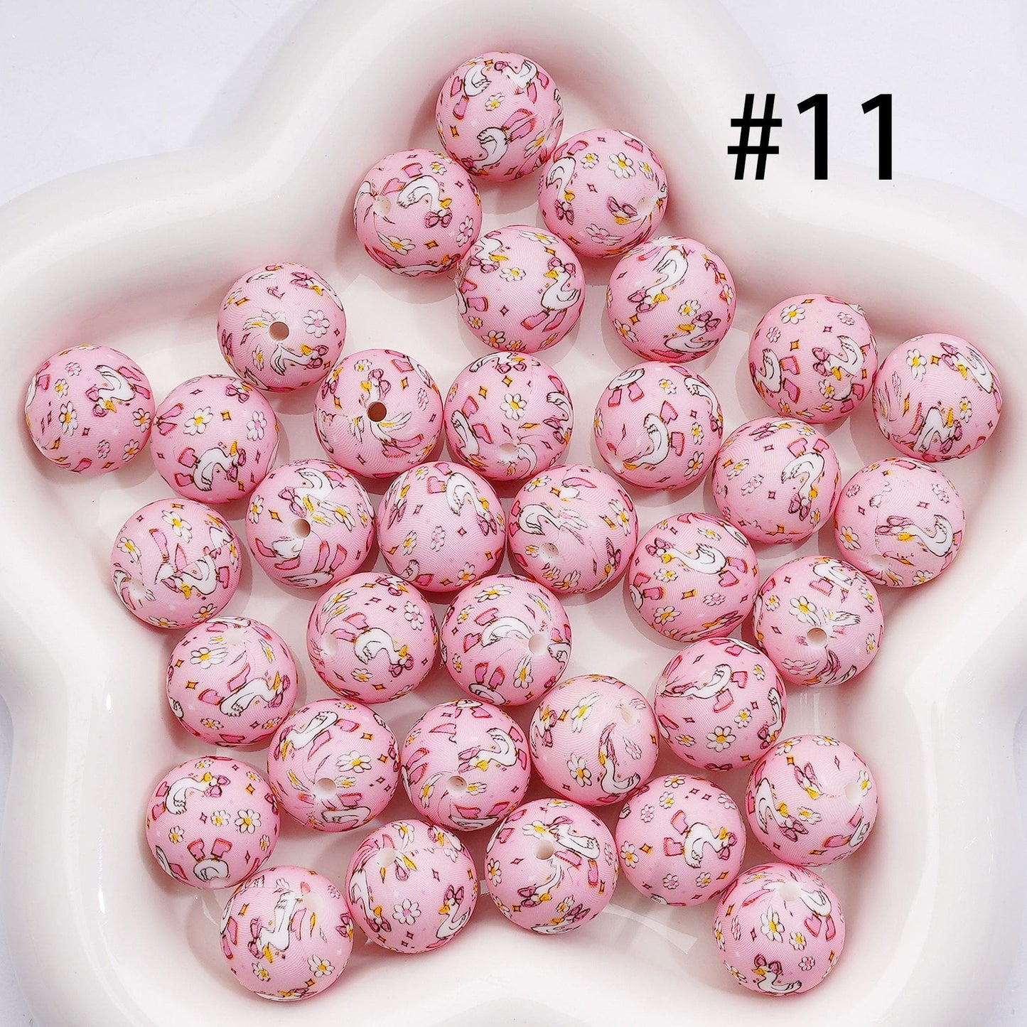 Pink beads with unicorn designs on a white surface