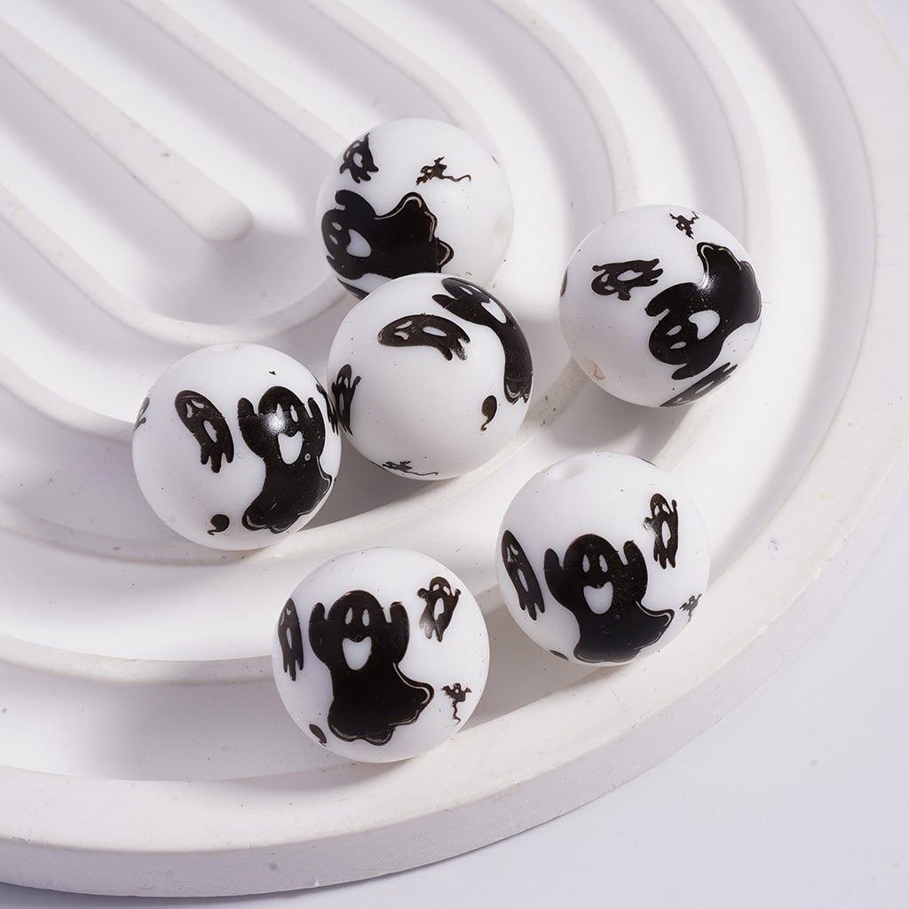 White beads with black ghost designs on a white background