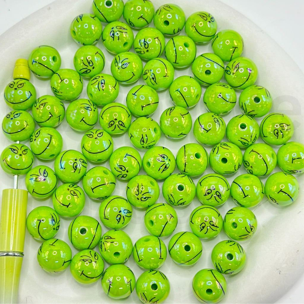 Green beads with face designs on a white plate