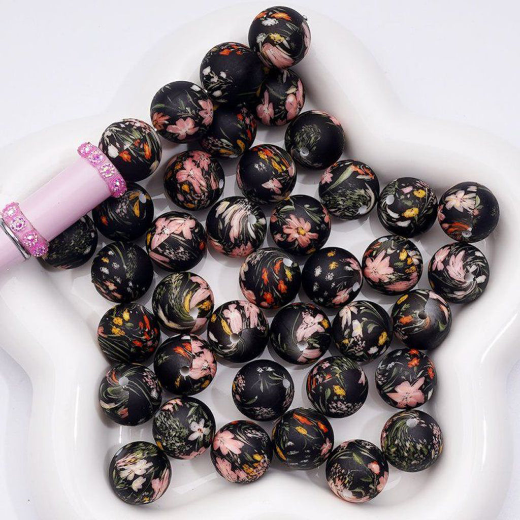 Black beads with floral patterns on a white surface