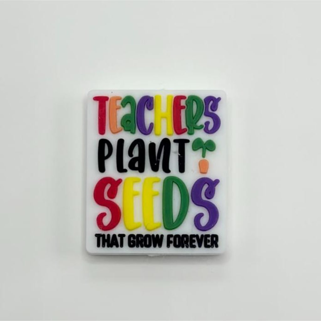 A silicone bead with the text 'Teachers Plant Seeds That Grow Forever' printed on it, primarily in green color with multicolored letters and decorative elements.