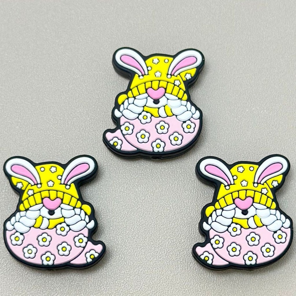 黄色い帽子をかぶったかわいいウサギが、割れた花柄の卵の中に座っています。イースターのシリコン製フォーカルビーズです。